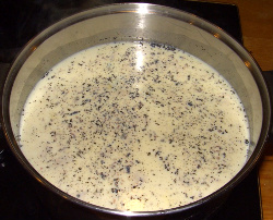 Vanilla beans floating on top of heating milk.
